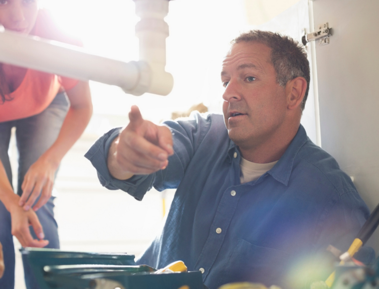 Image of a male contractor checking the drain under the sink